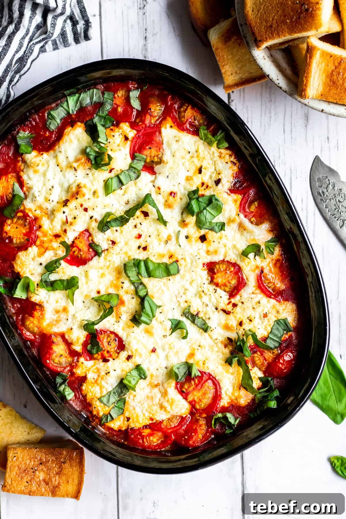 Baked Goat Cheese Dip with Marinara: Creamy Oven-Baked Recipe 6 Wide overhead shot of dip on white counter with bread and towel surrounding it.