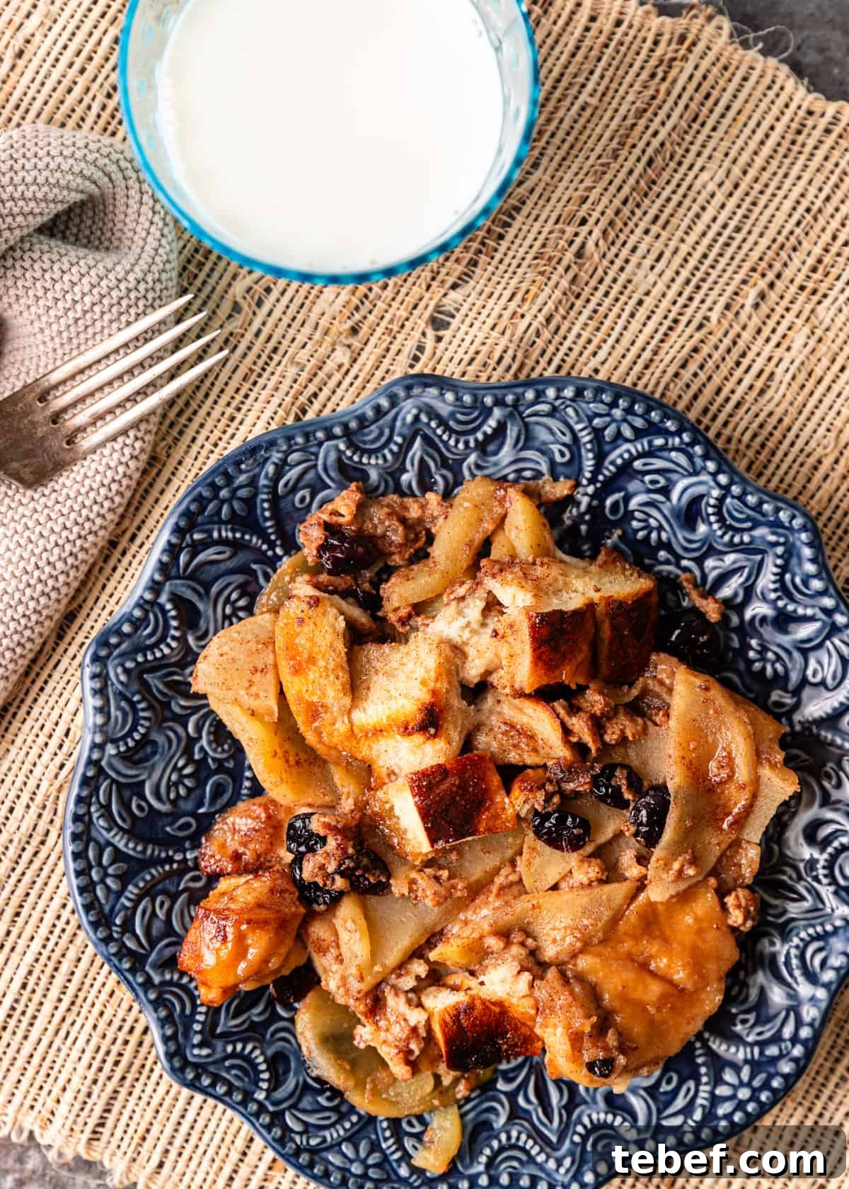 Mom’s Overnight French Toast Casserole Recipe for Busy Mornings 10 overhead: a blue ceramic plate full of French toast casserole with a glass of milk and a fork to the side
