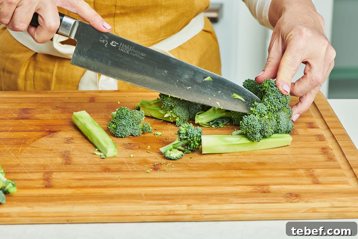 How to Trim, Chop, and Cook Broccoli for Perfect Results 3 Woman cutting broccoli on wood board.