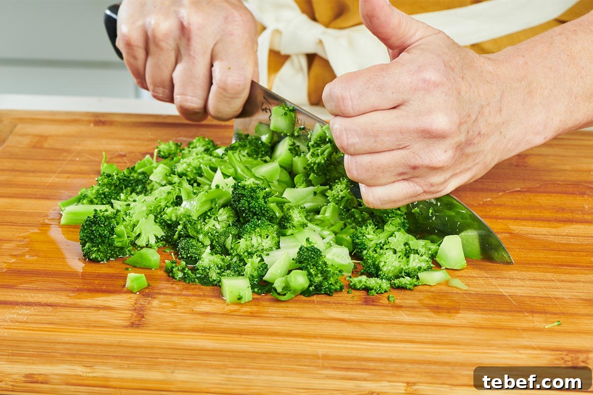 How to Trim, Chop, and Cook Broccoli for Perfect Results 6 Chopping broccoli on cutting board with knife.