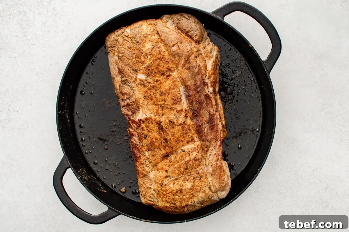 Perfect Oven-Roasted Pork Loin: Juicy, Crispy Recipe and Tips 5 The seasoned pork loin is in a cast-iron skillet on the stovetop, searing to develop a golden-brown crust.