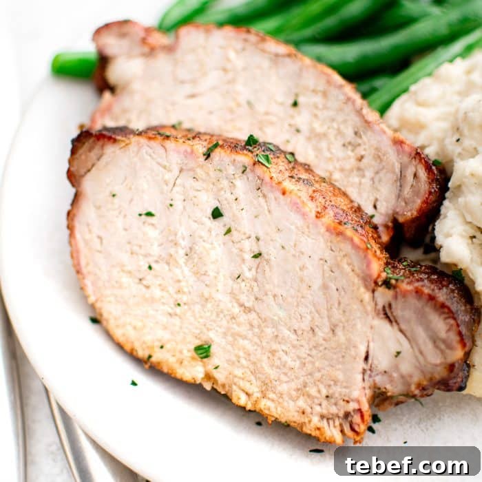 Perfect Oven-Roasted Pork Loin: Juicy, Crispy Recipe and Tips 9 A detailed close-up of two thick slices of pork loin, showing the juicy interior and seasoned crust. The slices rest beside smooth mashed potatoes and vibrant green beans, all on a white plate.