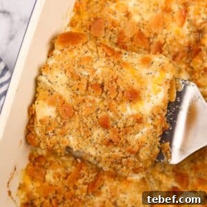 Lifting creamy chicken casserole from a baking dish using a spatula.