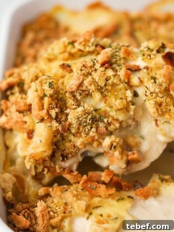 Lifting a piece of chicken and stuffing from a baking dish.