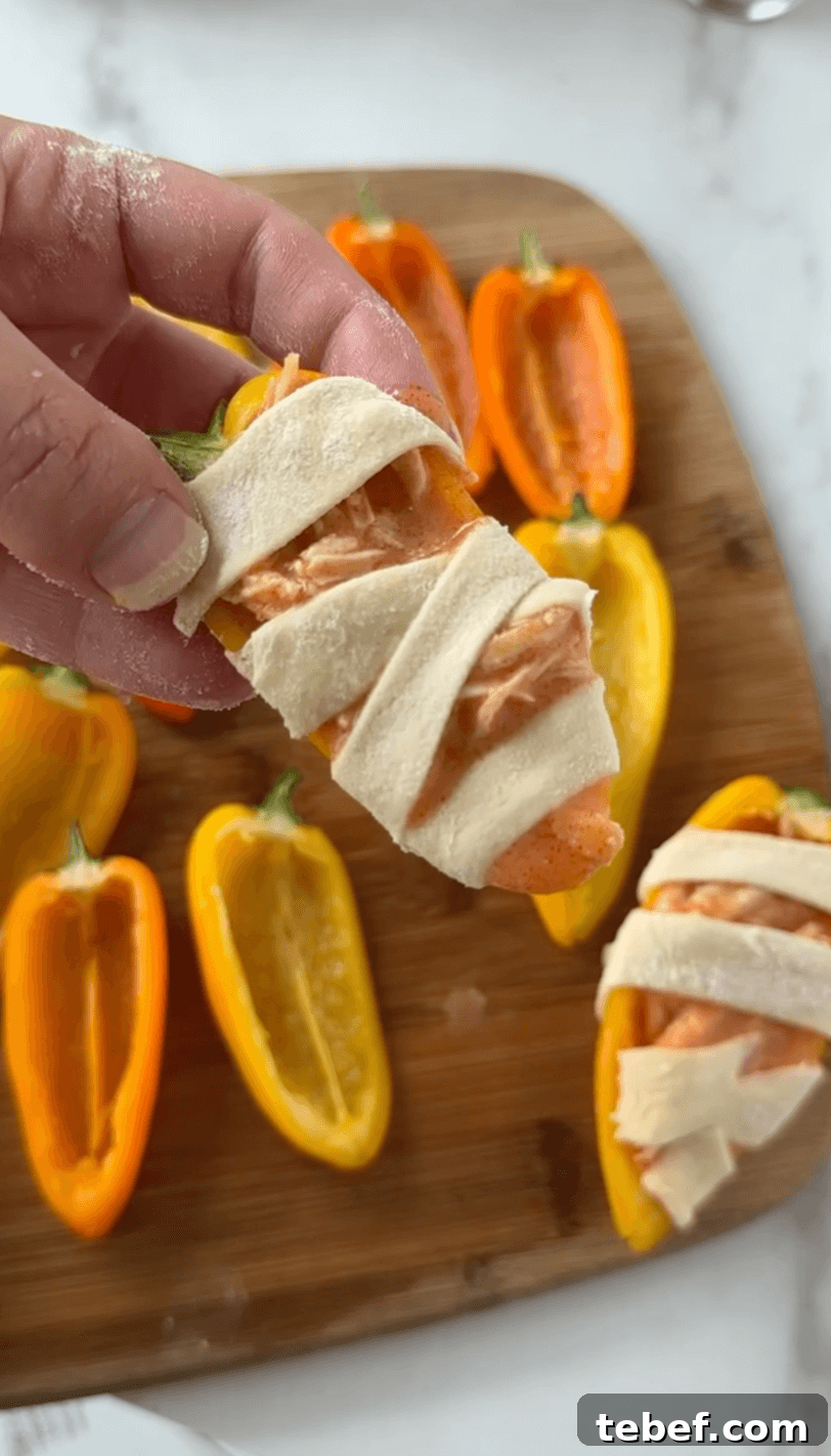 Wrapping the mini bell pepper with the dough to look like mummies