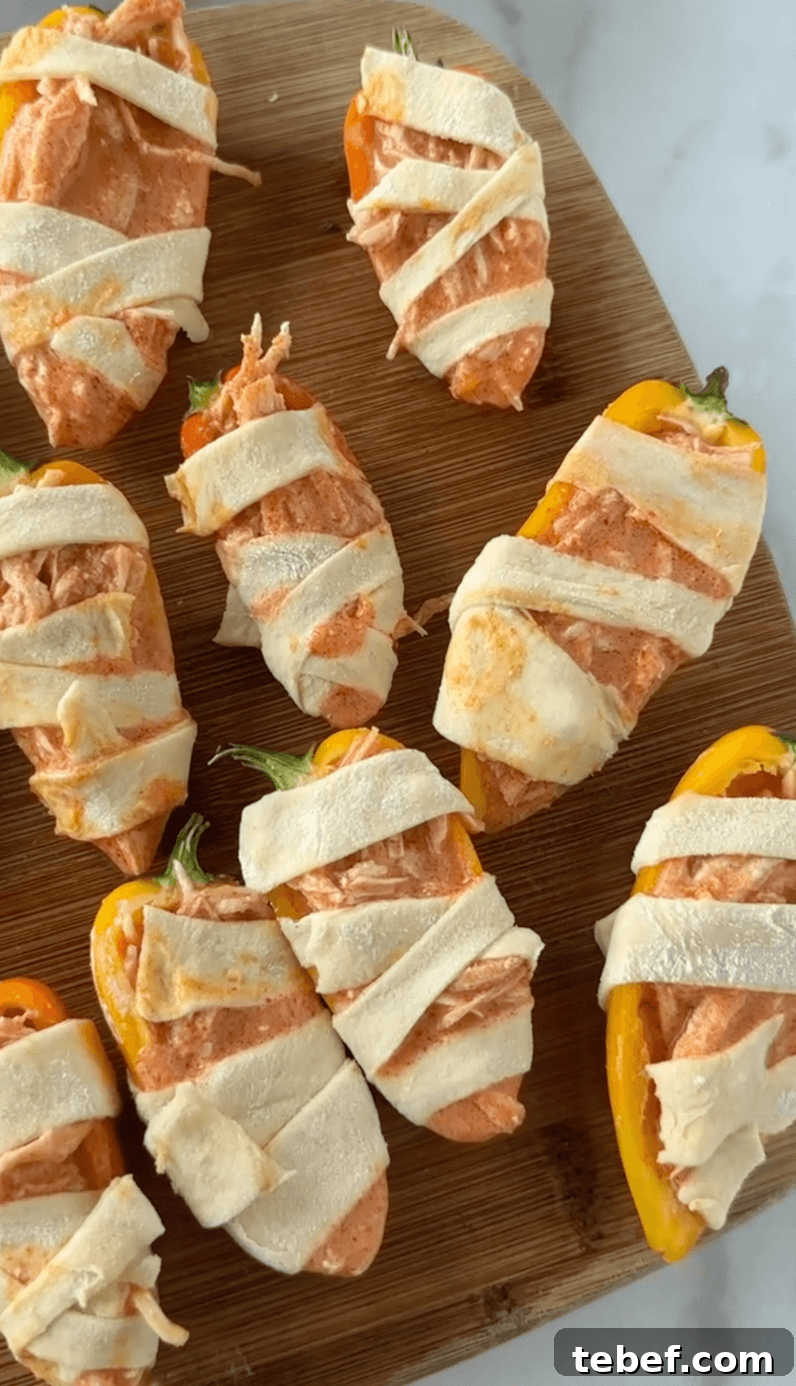 Board of wrapped bell pepprs into mummies before cooking