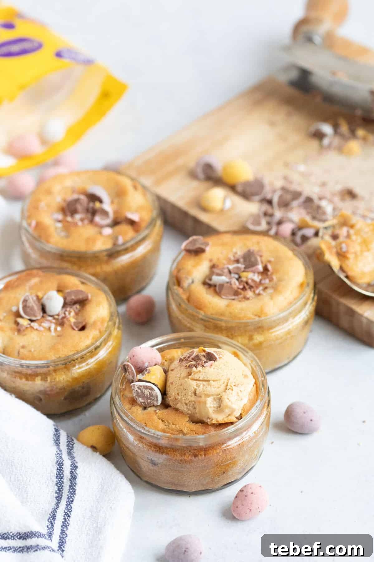 4 mini egg dessert pots in glass ramekins with ice cream and crushed mini eggs.