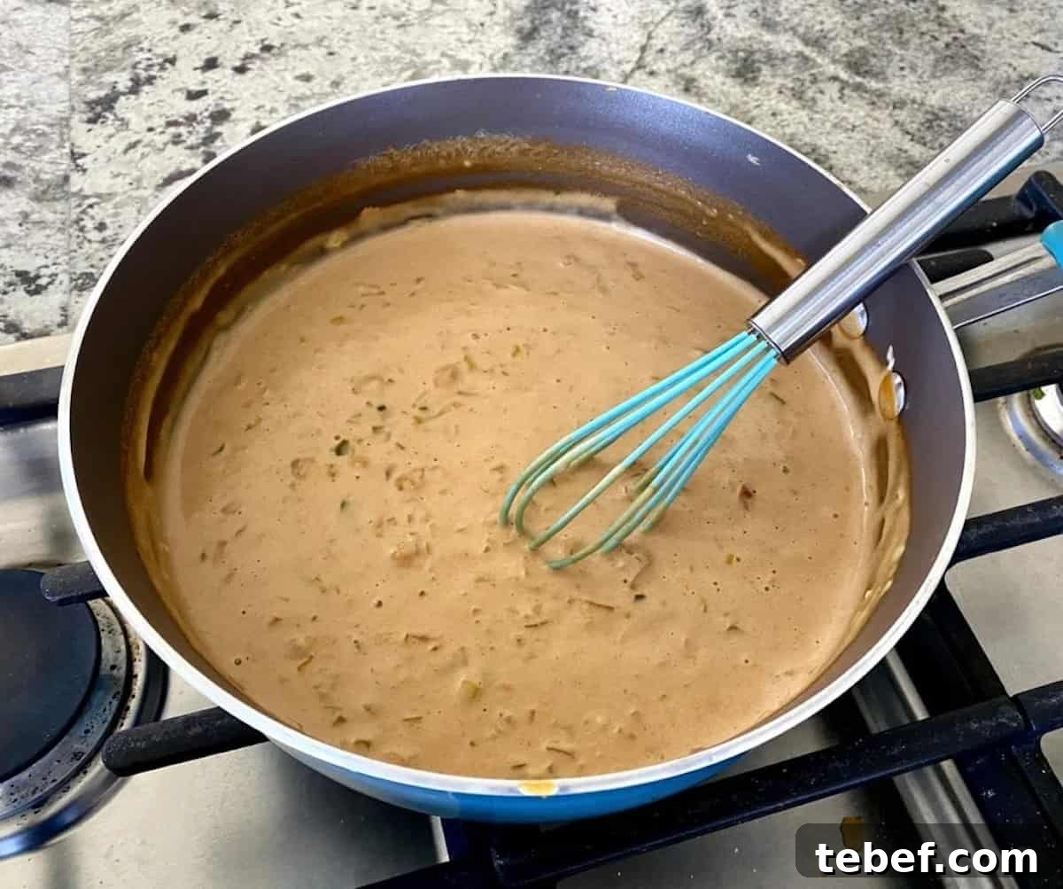 Creamy mushroom sauce in a pan with a whisk.
