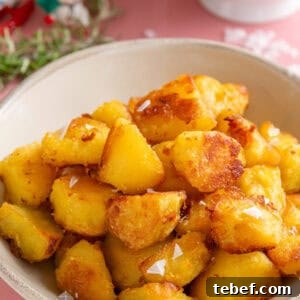 A bowl of crispy roast potatoes with a sprinkle of sea salt flakes on top.