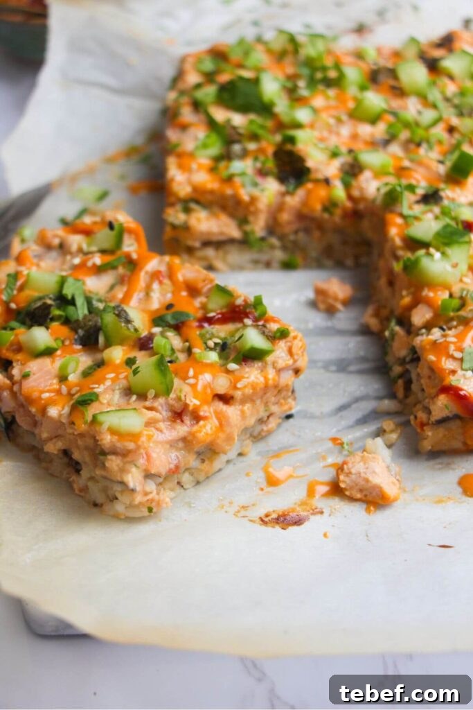 A slice of sushi bake with more salmon sushi bake in the background.
