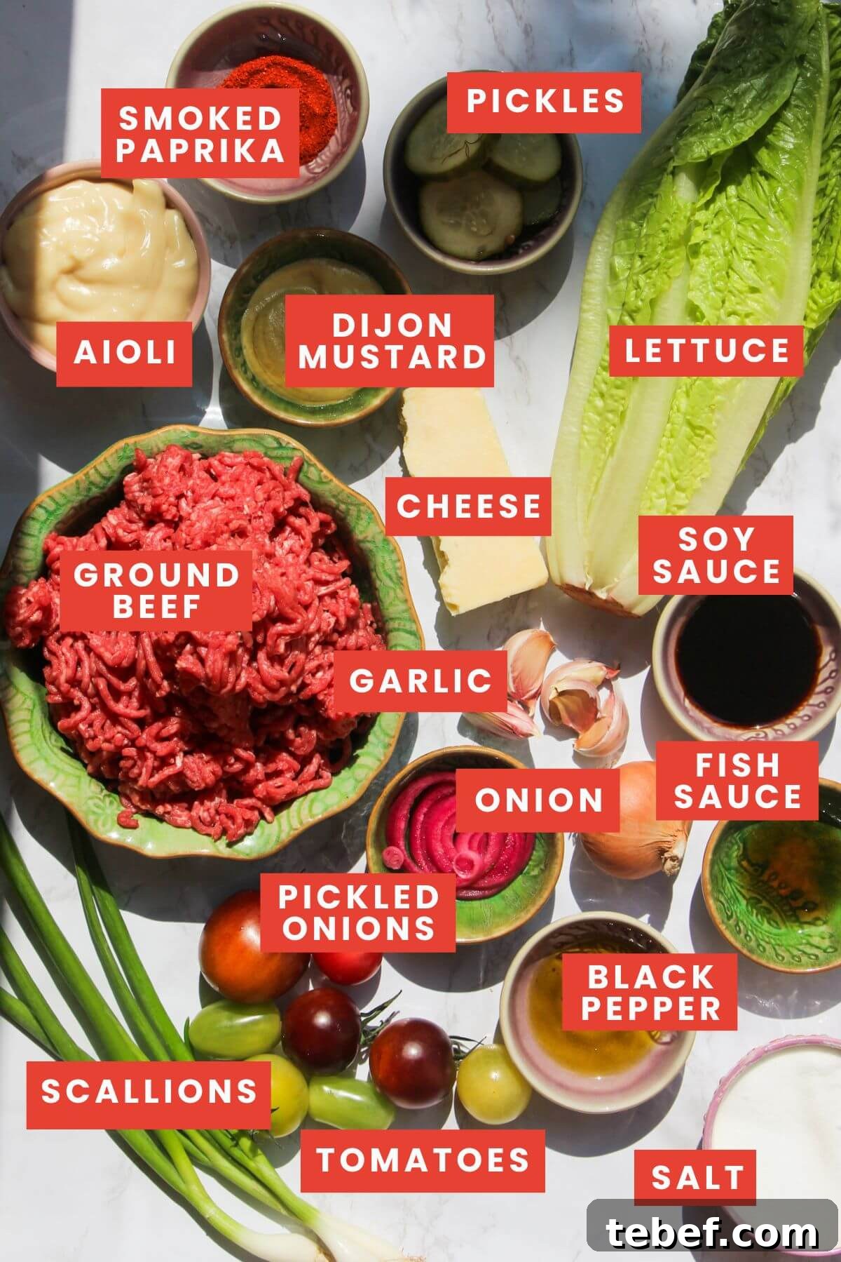 Ingredients for Big Mac salad bowl laid out on a white marble background and labelled.