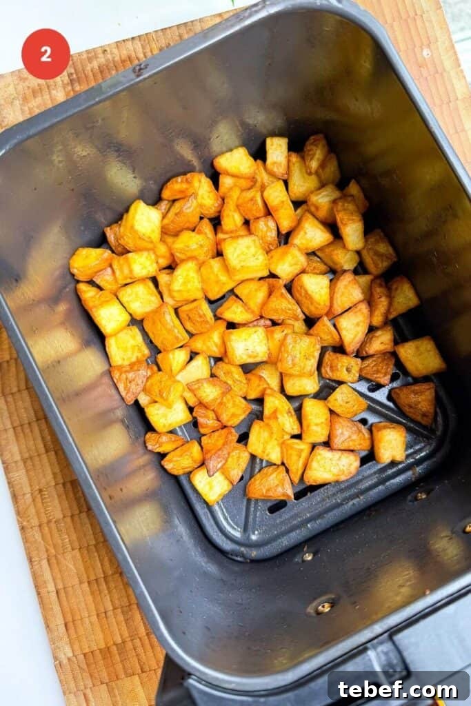 Air fried cubed potatoes in air fryer basket.