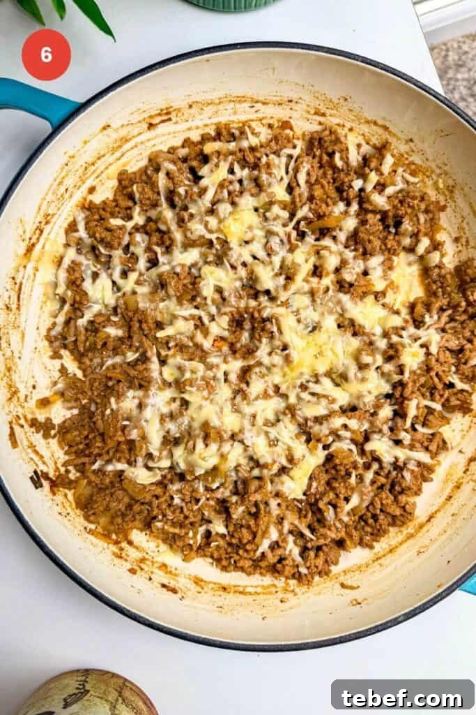 Cheese melted over cheeseburger beef in a pan.