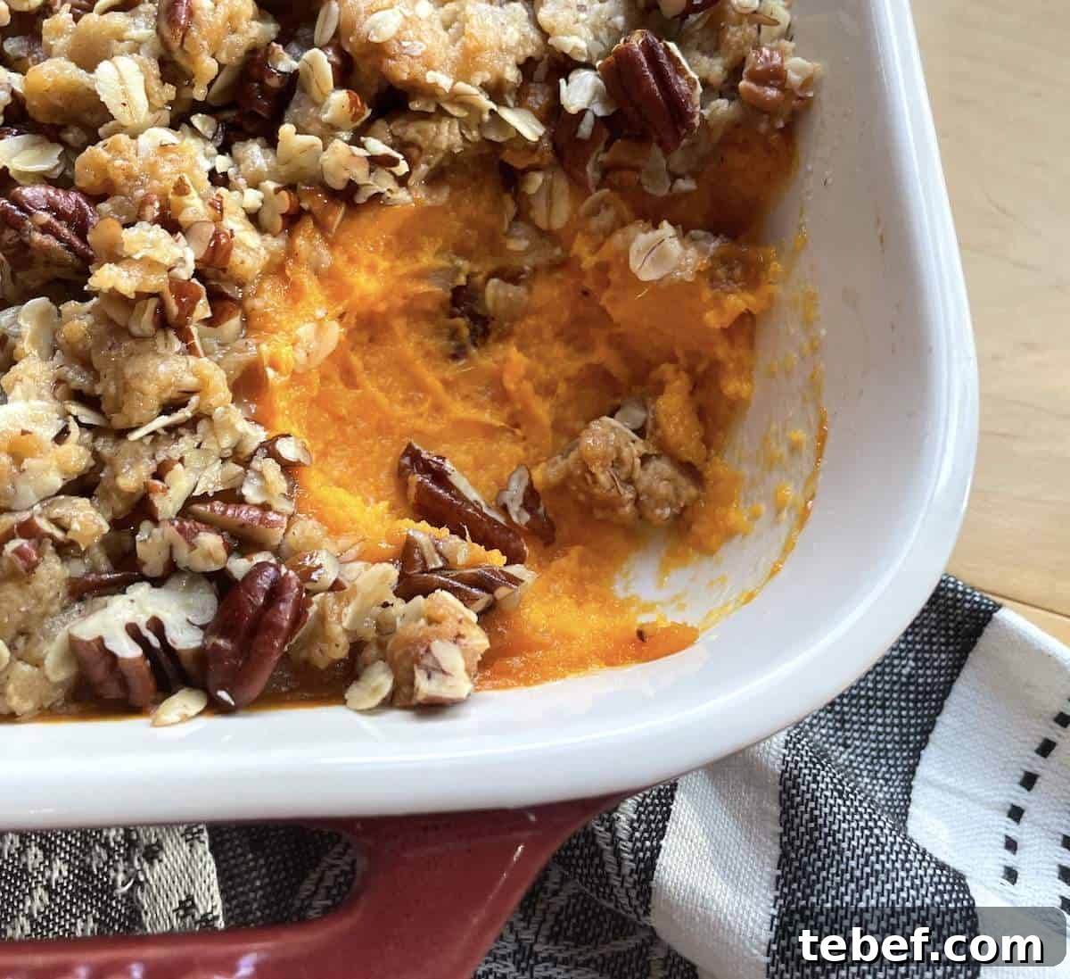 A pan of sweet potato casserole with a scoop missing.