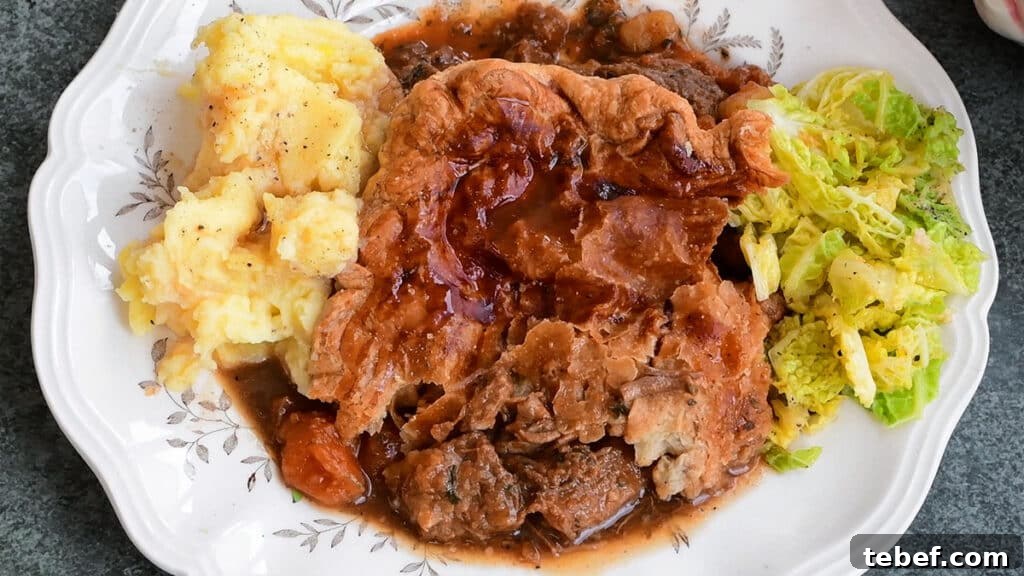 serving of Irish meat pie on a plate with mashed potatoes and cabbage