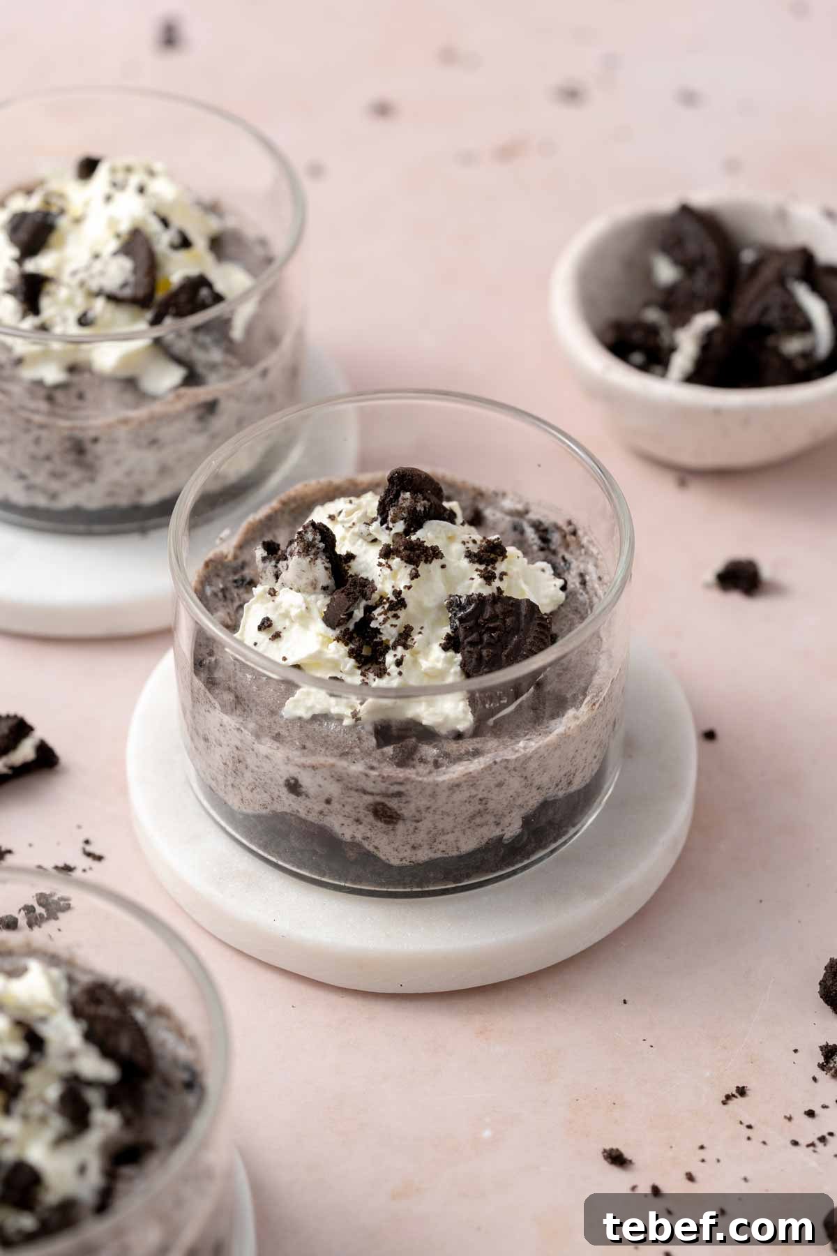 An angled view of a jar of no-bake Oreo cheesecake cup with more off to the side.