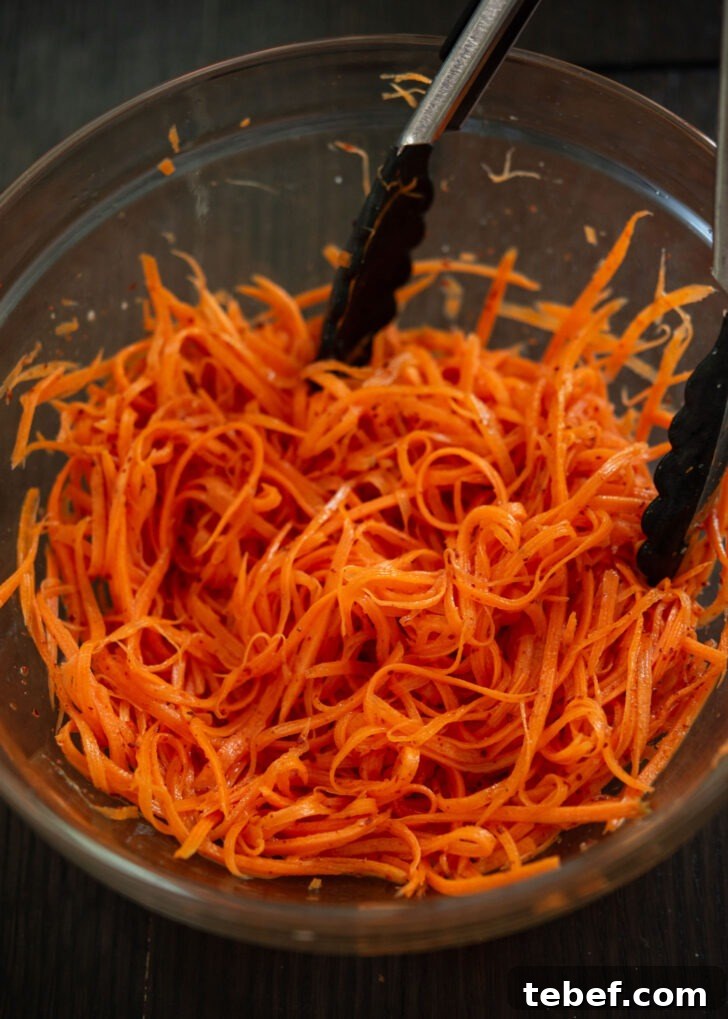 Gochugaru added to the carrot mixture in a bowl.