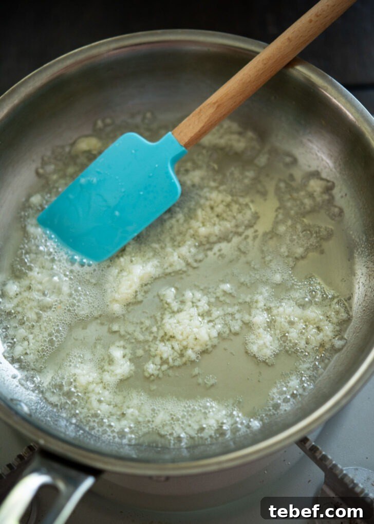 Garlic frying in oil in a skillet.