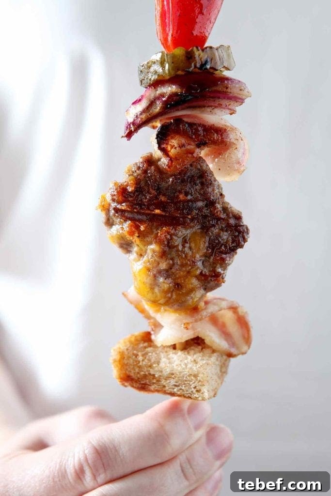 A woman holds a cooked Cheeseburger Kebabs in her hand