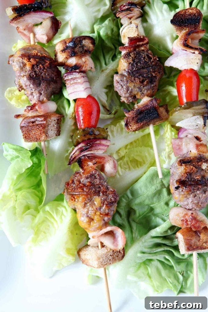 Close up of cooked deconstructed burger bites on skewers, laid out on lettuce