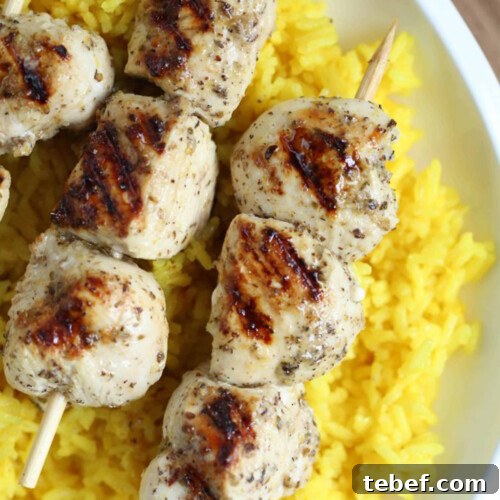 greek chicken kabobs on top of golden rice