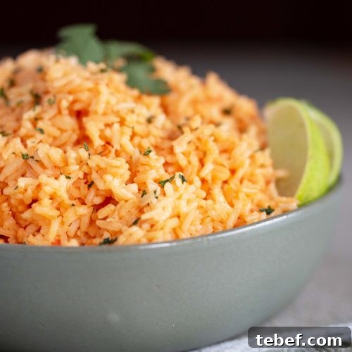 Mexican rice in a green bowl, garnished with slices of lime
