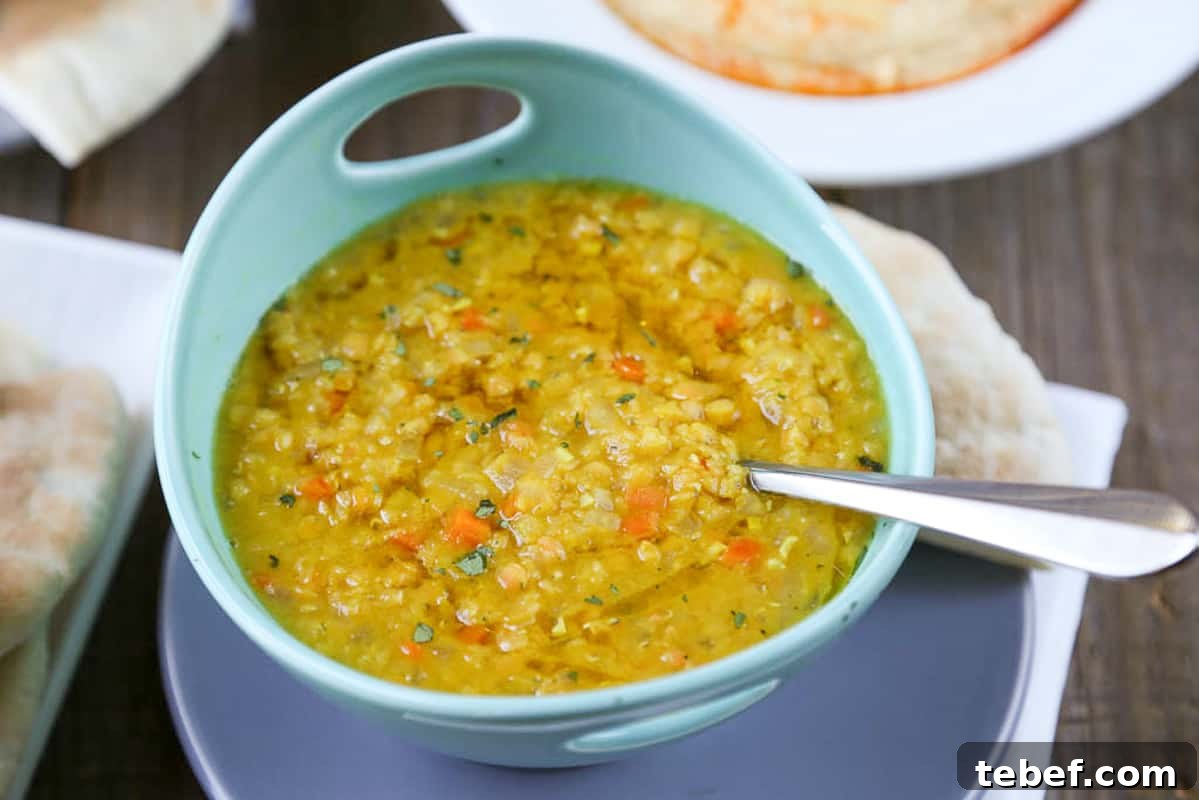 lebanese lemon lentil soup with a spoon in it, in a turquoise bowl.